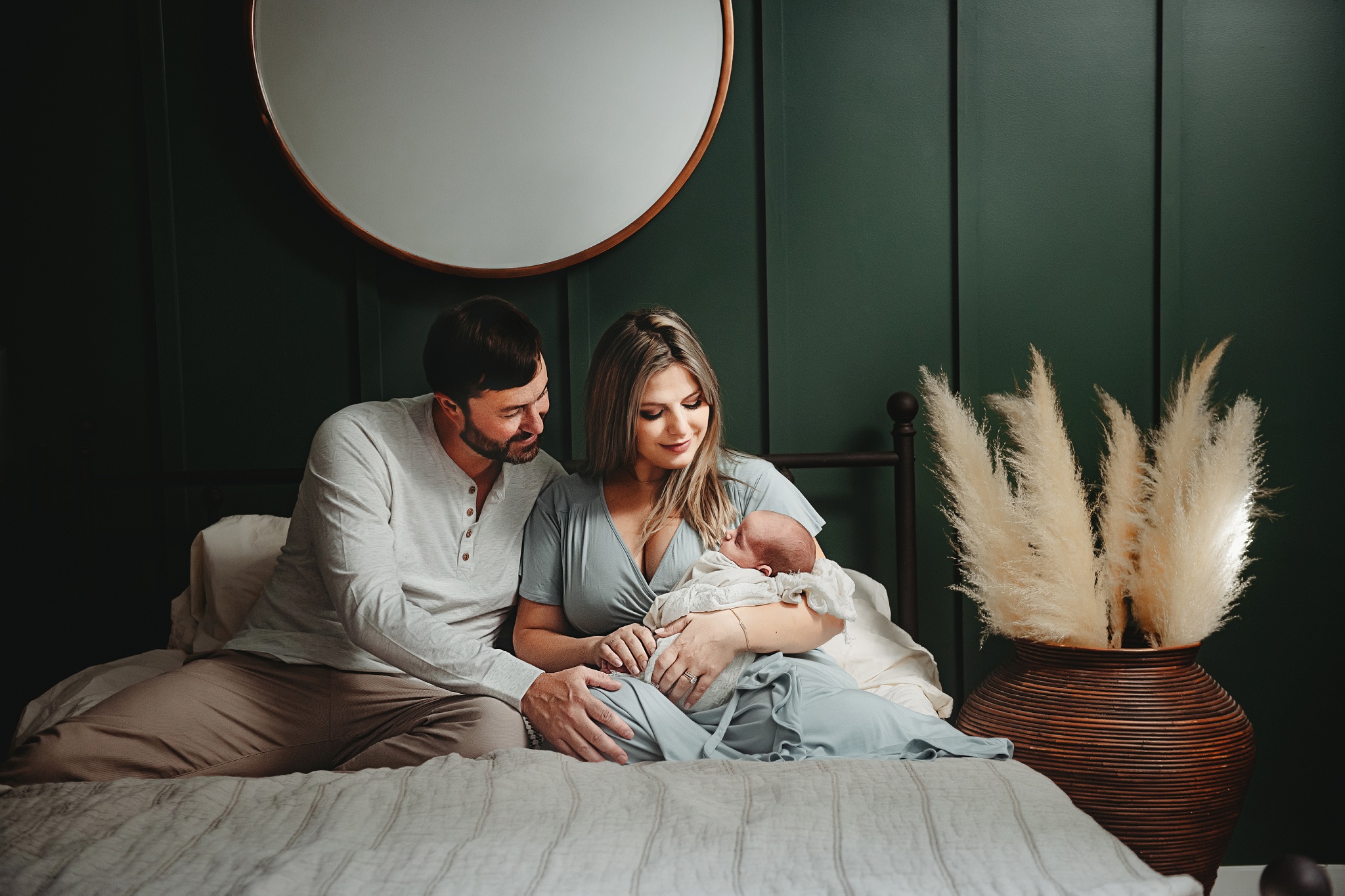 young family holding newborn baby with rich colors in home