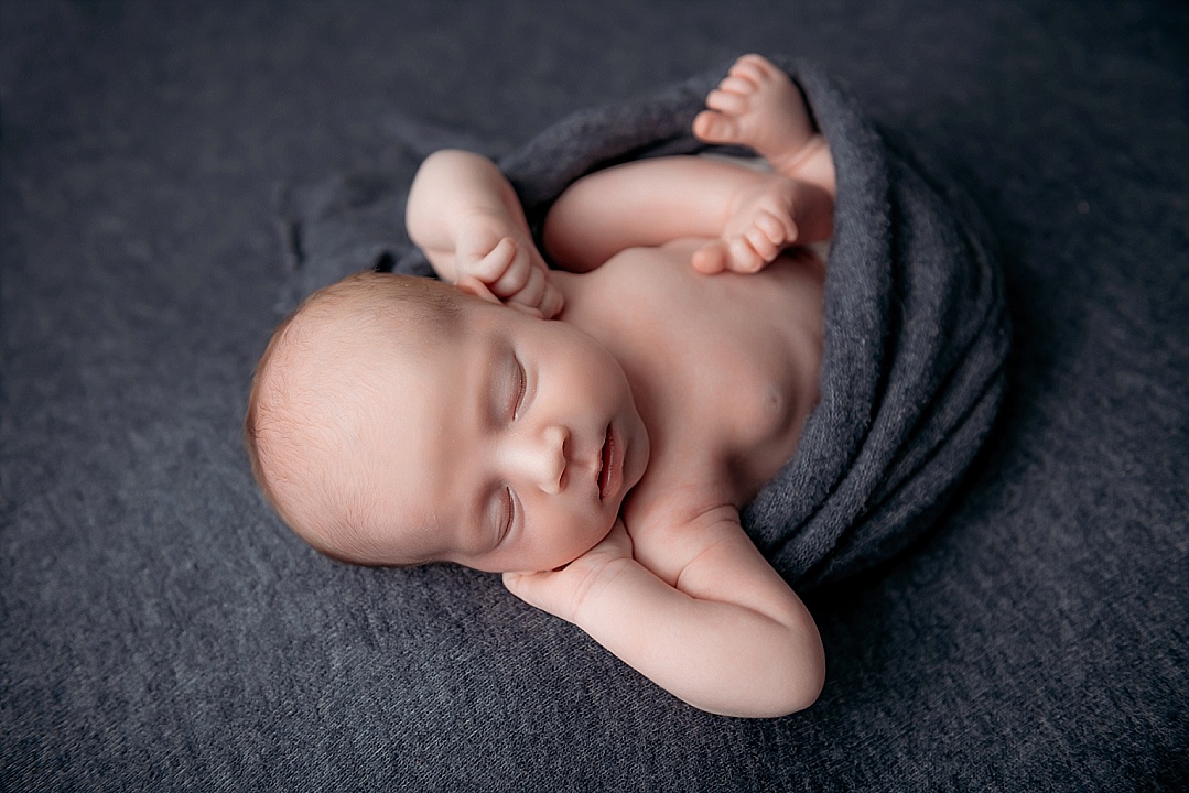 newborn baby laying in grey blanket for newborn photography session in Maryland