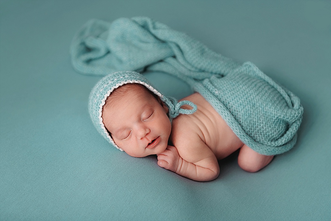 newborn baby in teal bonnet and matching blanket for Annapolis photo session