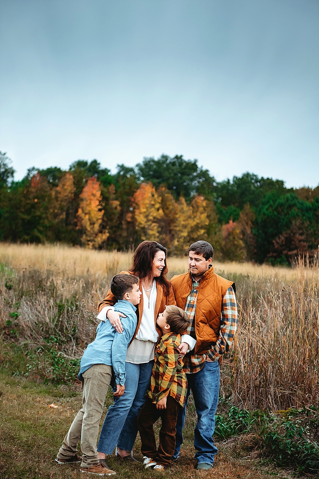 family with two older boys for fall photos in Maryland in field