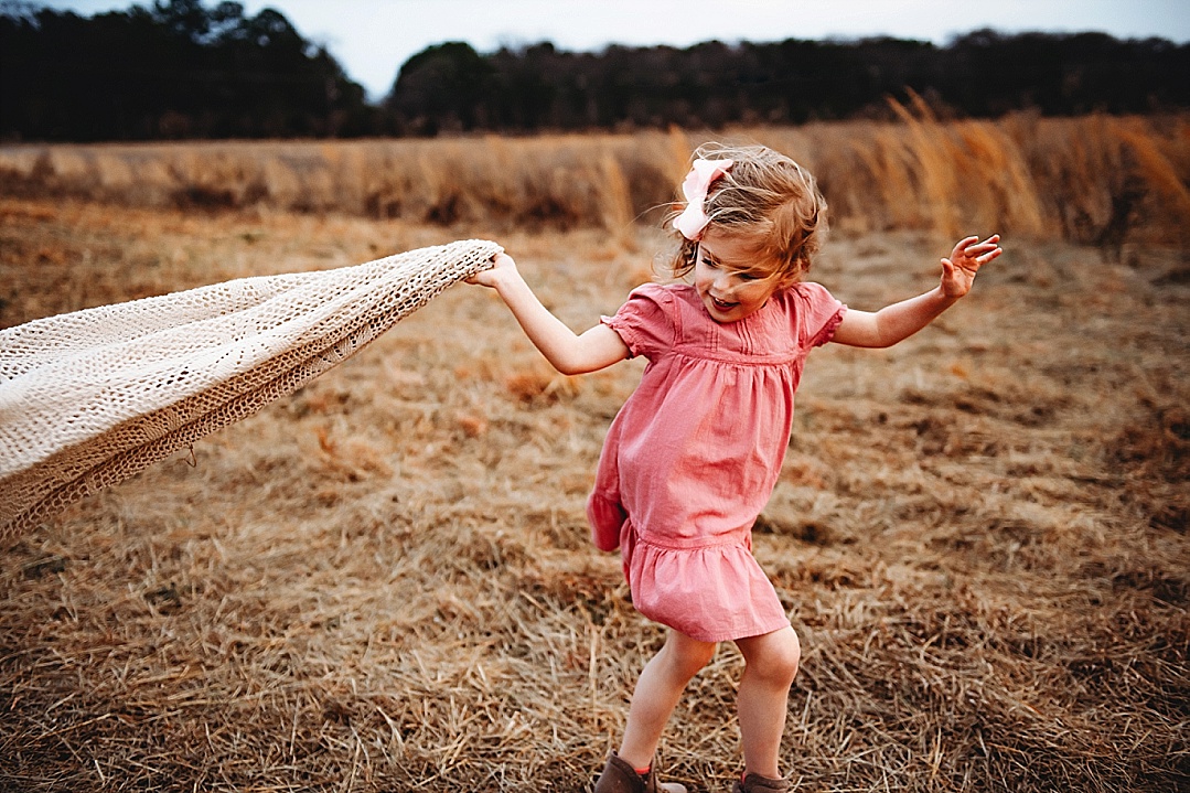 imaginative play girl in pink dress running with blanket
