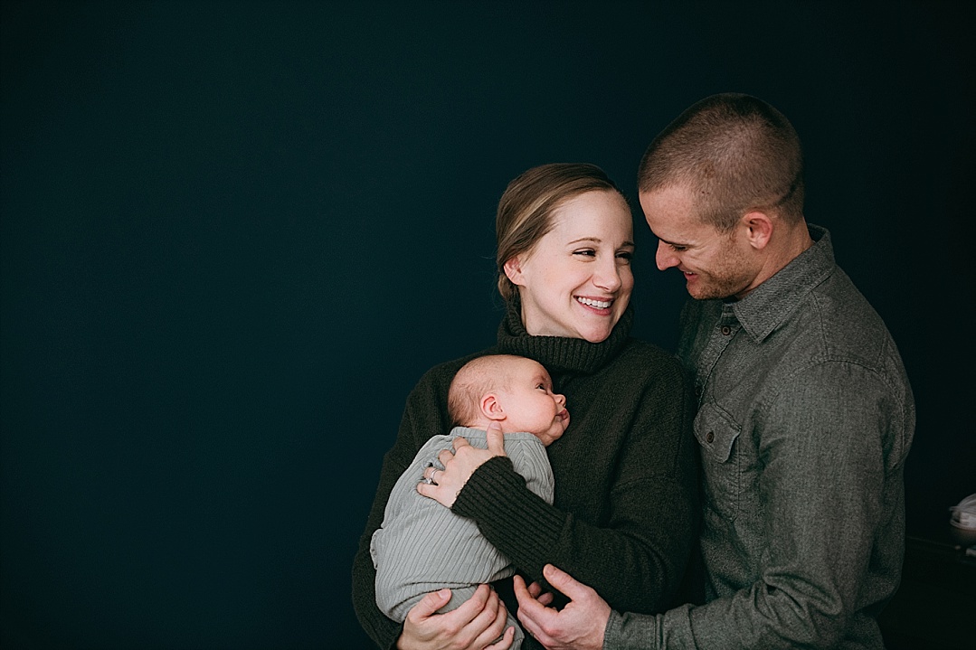 new parents holding baby black background