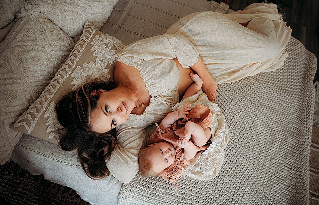 mom in off white dress boho with baby on bed