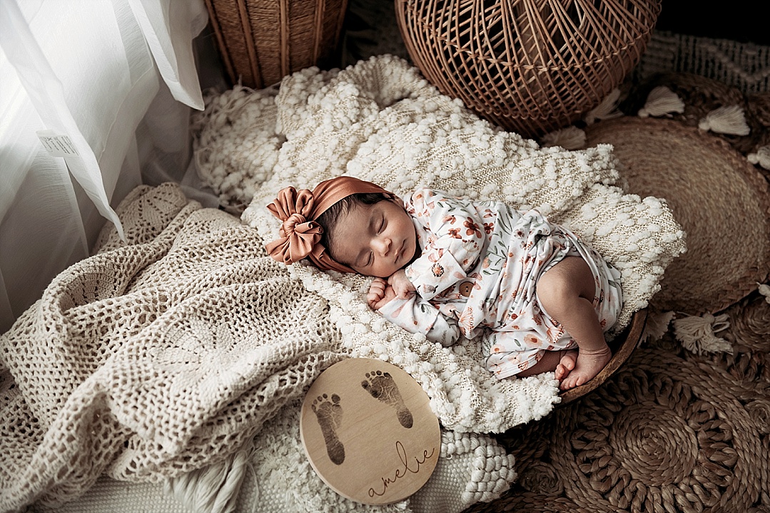 newborn baby girl in flower onsie boho theme in Kent Island photography studio with foot prints