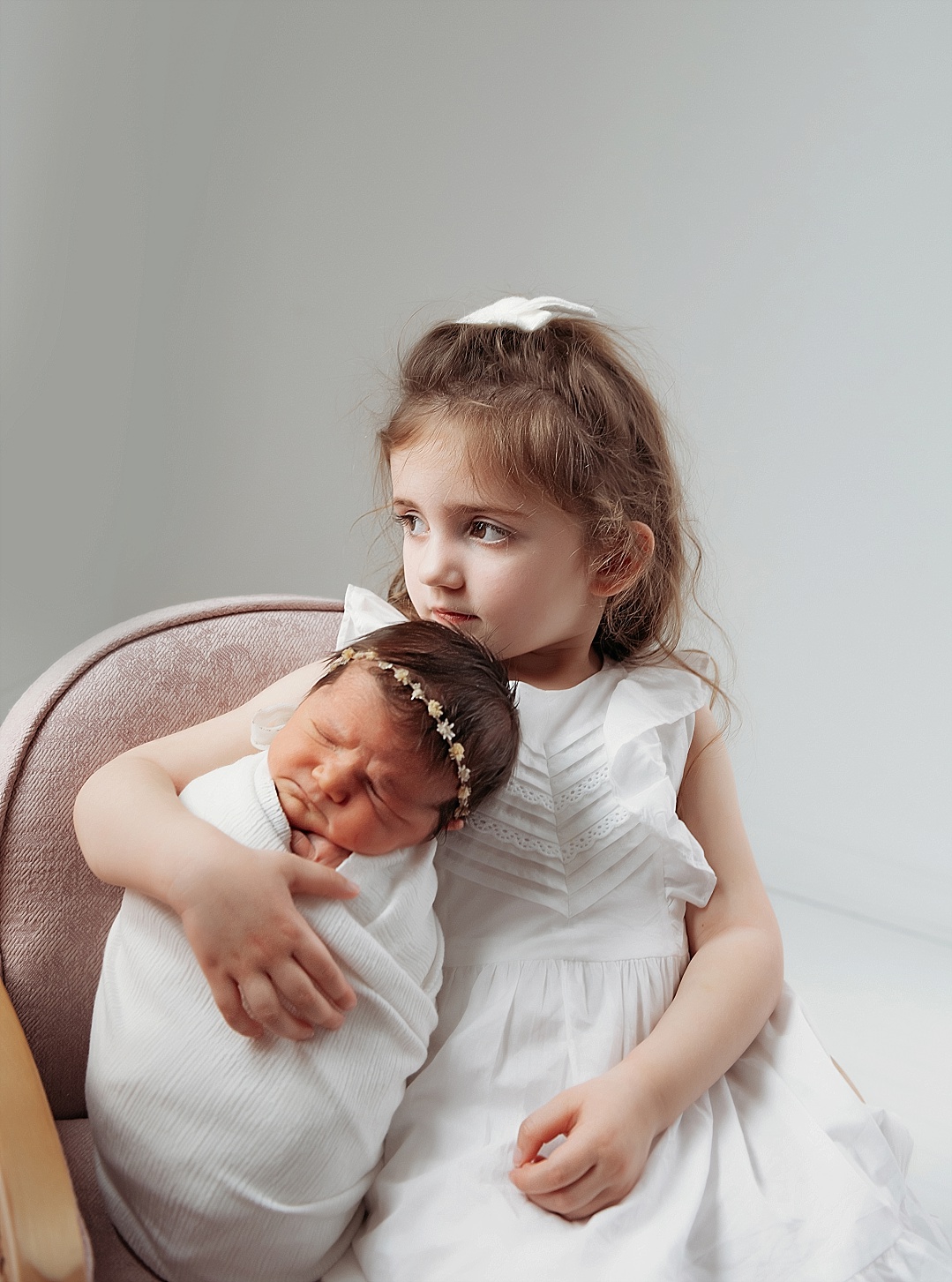 newborn sister with older sister in whites and rose with white headbands for Annapolis studio newborn session