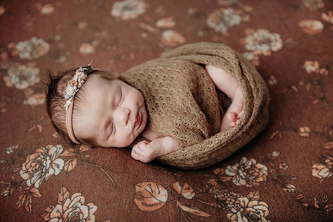 new baby girl on rust background with flower head band for Kent Island Maryland Photography newborn session